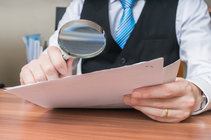 man wearing suit reviewing document with magnifying glass, types of discovery, civil litigation