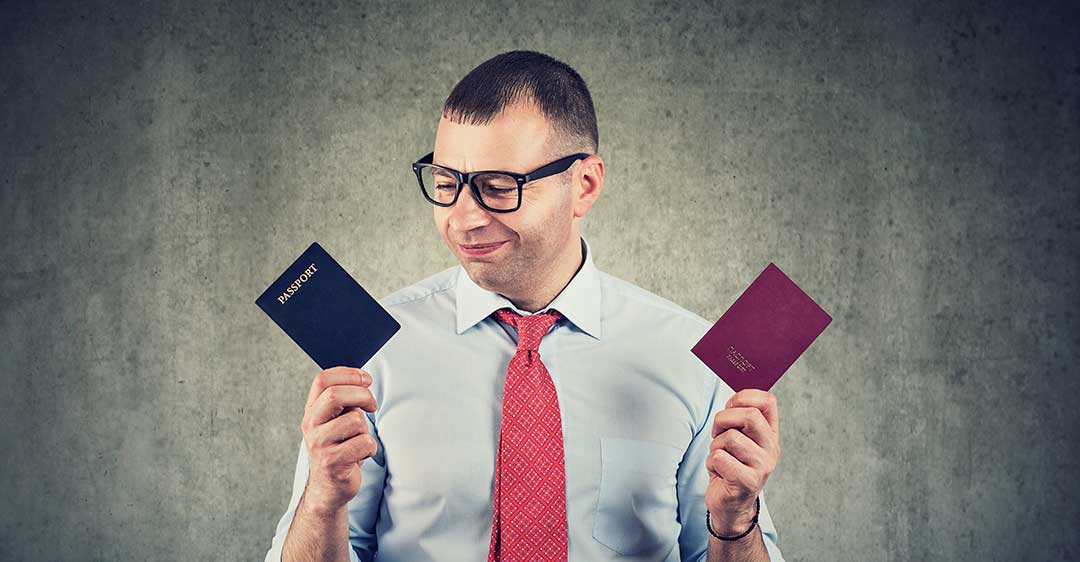 man with glasses wearing red tie holding two passports, benefits to alternative citizenship