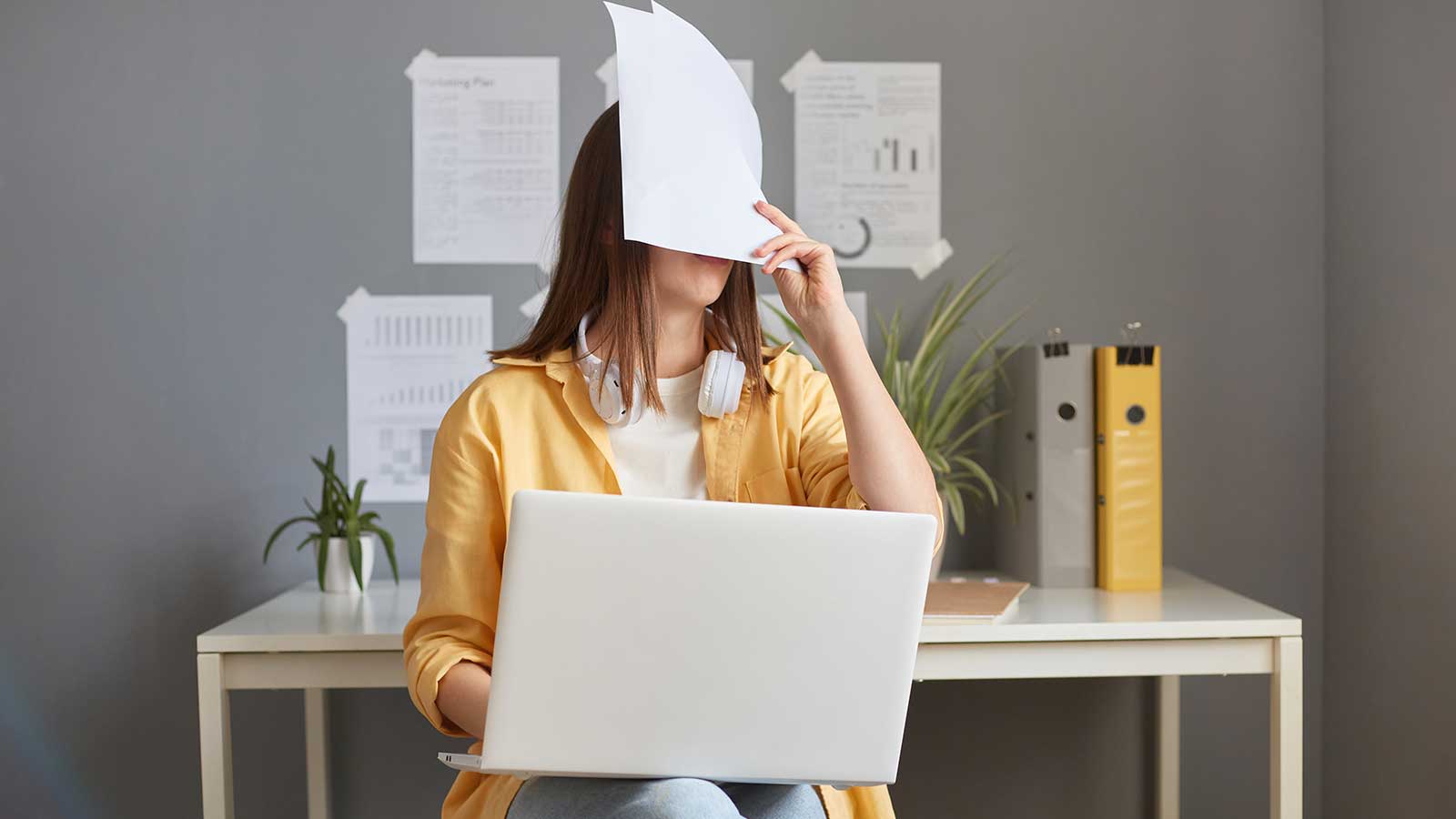 woman working with documents and laptop, covering face, immigration mistakes