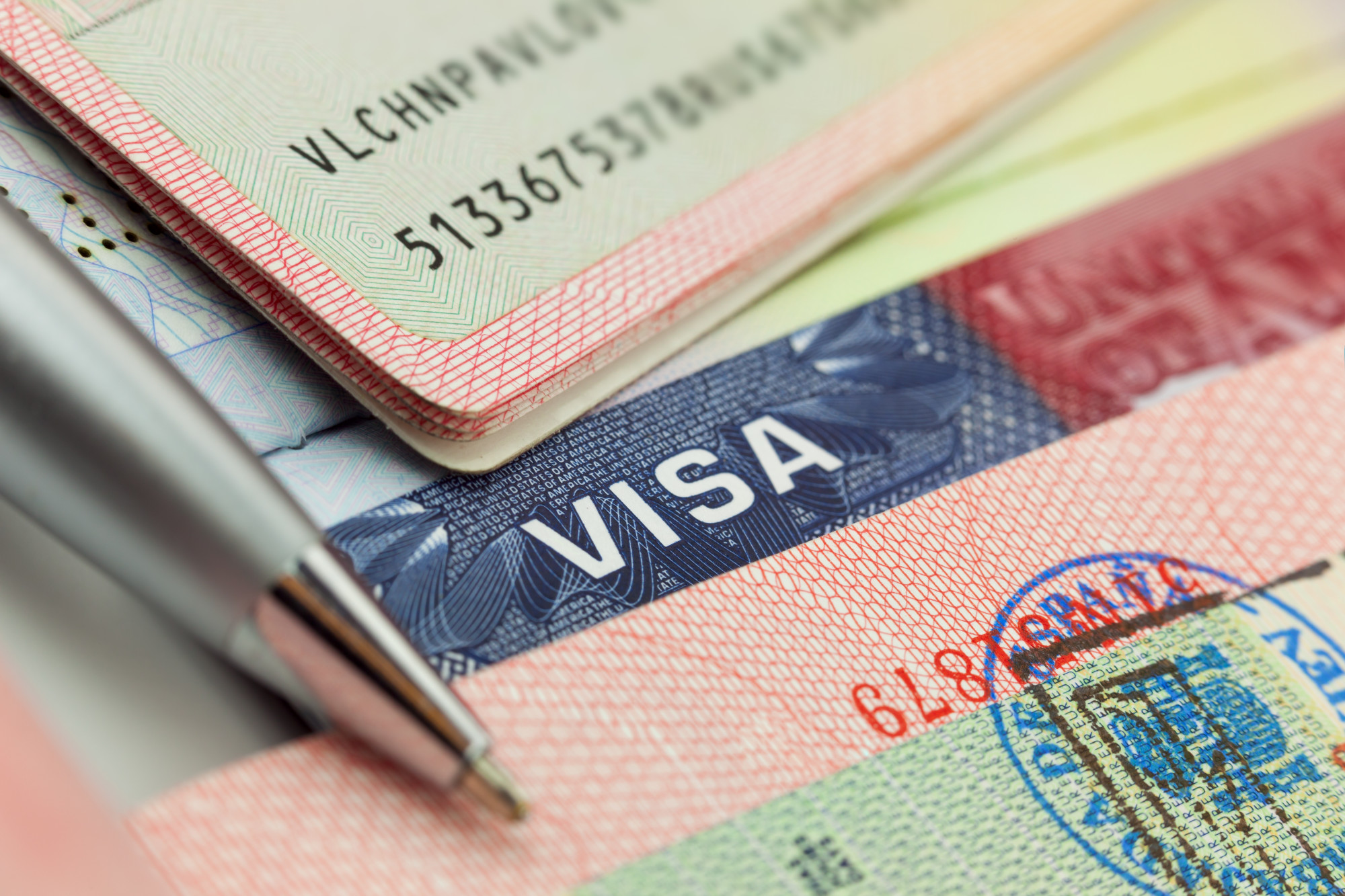 Different visas and stamps in a passport - travel background, E-2 investor visa policies, NDAA