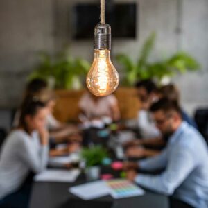lit lightbulb in foreground, background of business people meeting in conference room, incorporating a business in florida
