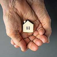 elderly woman hands holding a little toy house, property inheritance, summary administration, small estate