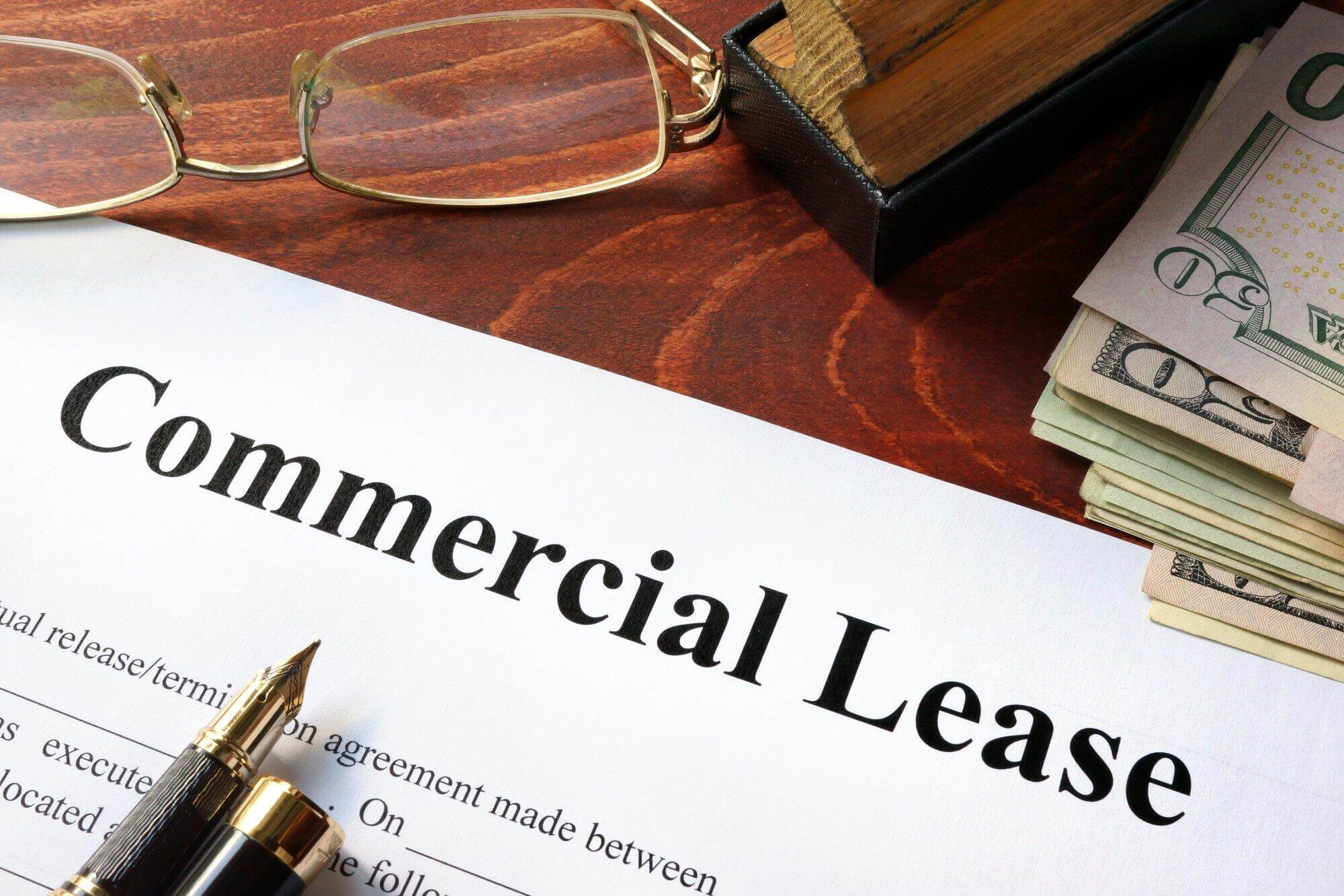 words commercial lease on document with pen, glasses, stamp and us dollars, commercial lease lawyer
