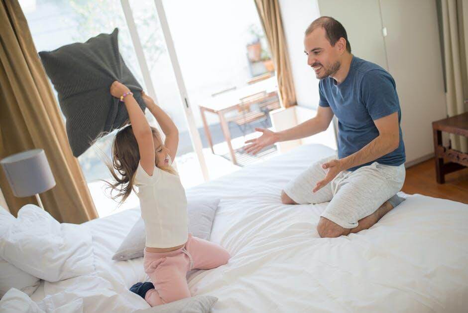 father and child playing on bed, child holding pillow, inheritance rights of stepchildren