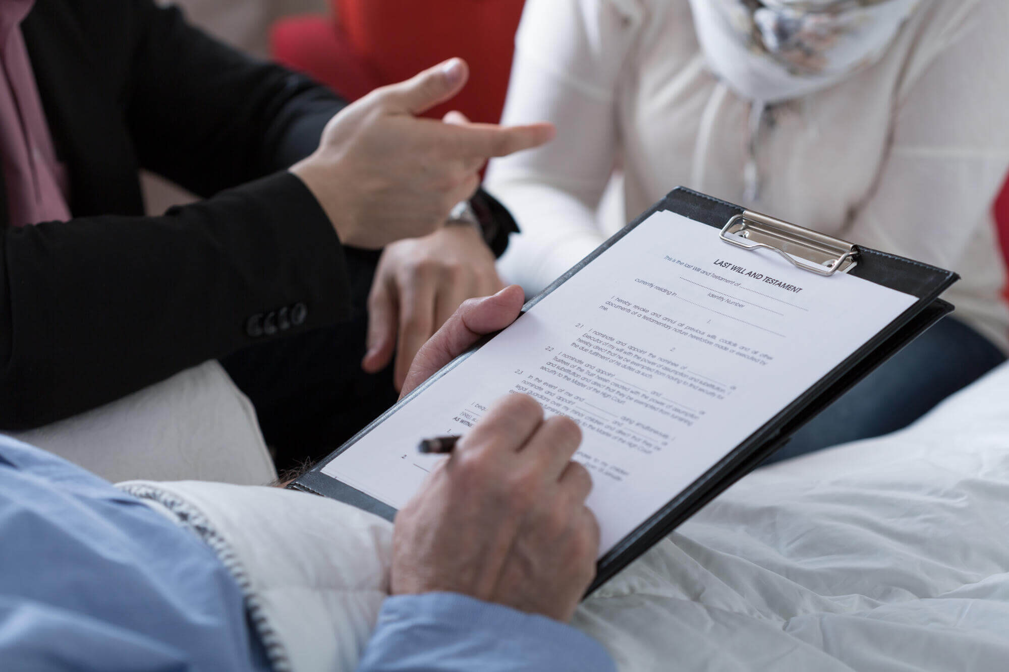 A person in a suit gestures while another holds a clipboard with a legal document titled Last Will and Testament, as a third person signs—consulting a civil litigation attorney Florida can help ensure your interests are protected.