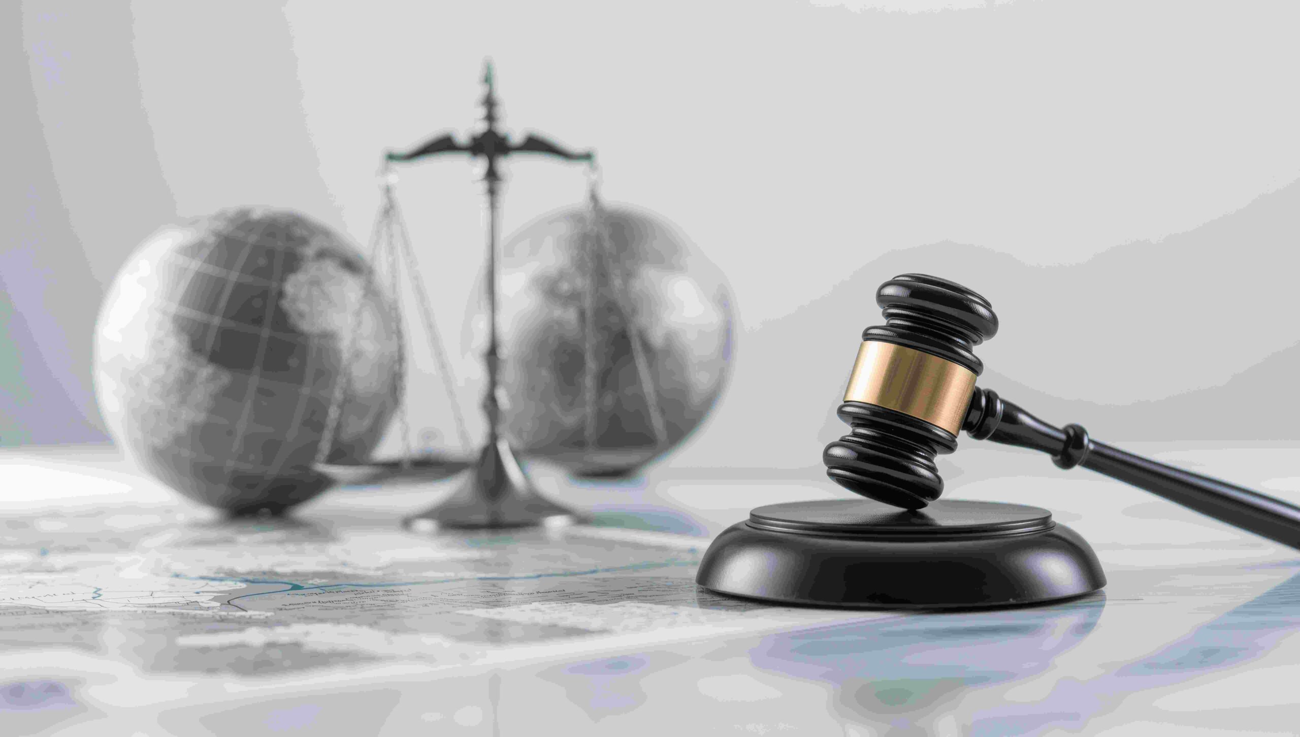 Gavel on wooden block with scales and global globe representing international law and justice