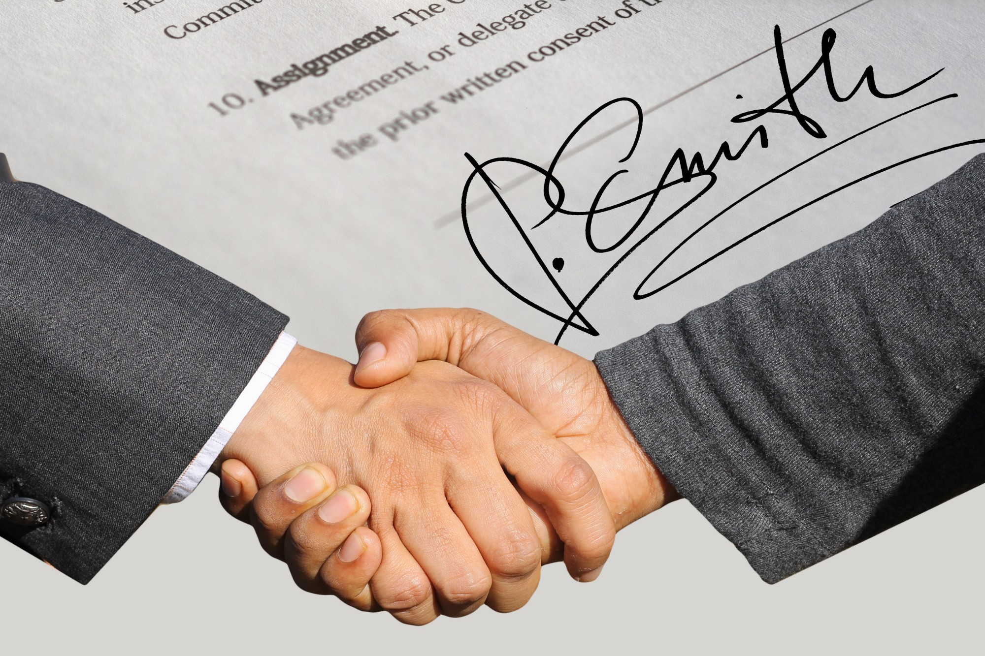 businessmen shaking hands with contract in background, contract mistakes