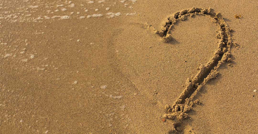 beach sand, water washing away half heart drawn in sand, separation tips and tricks for expats